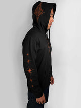 A man wearing a black pullover hoodie with orange graphic prints, shown in profile against a light gray background.