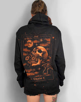 A person viewed from the back wearing an oversized black hoodie with a large tarot-style Death graphic in orange and brown tones across the back, against a plain light gray wall.