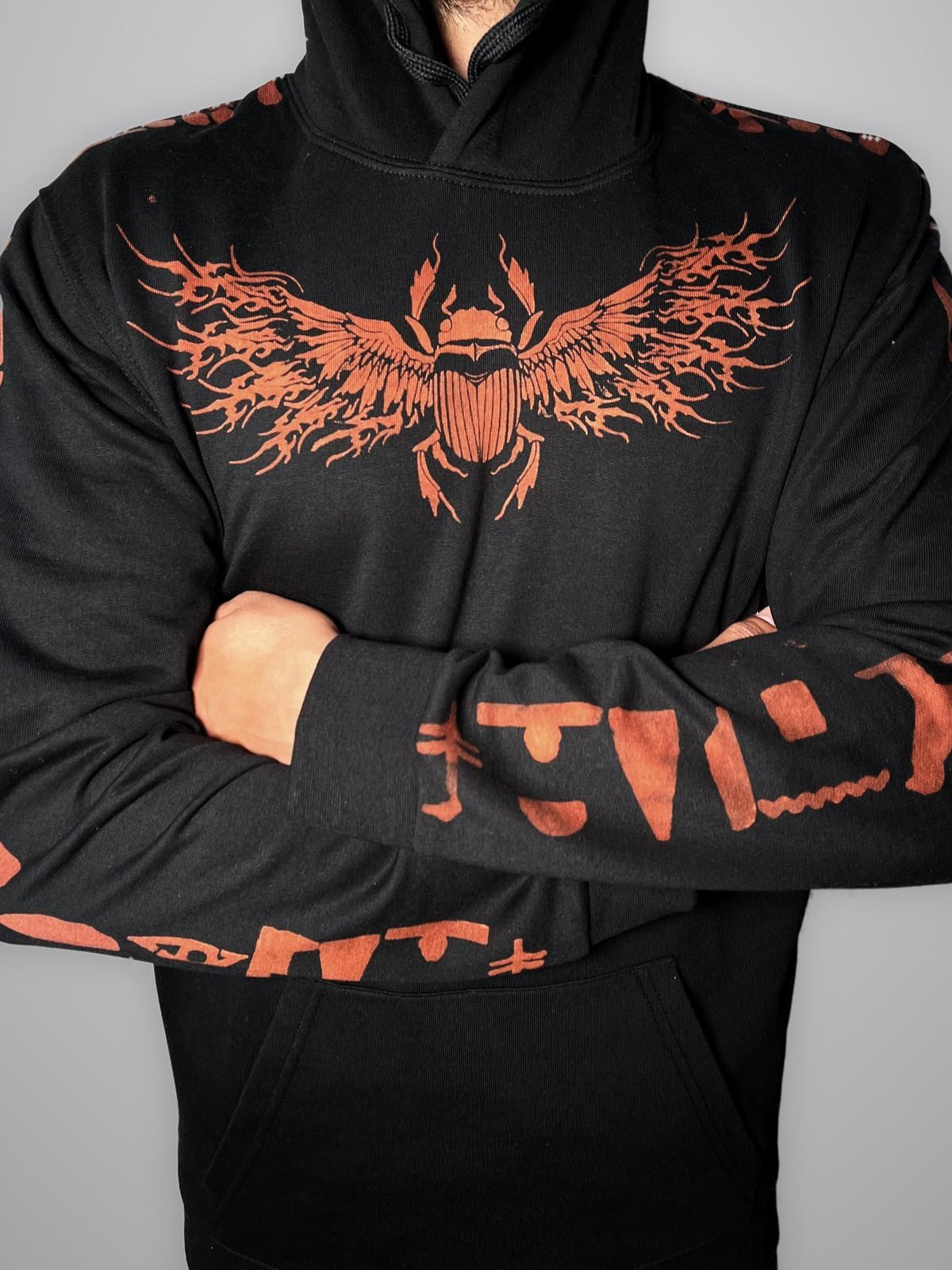Front of the Anubis hoodie with a winged scarab bleach-painted across the chest and hieroglyphs on the sleeves, worn by a model